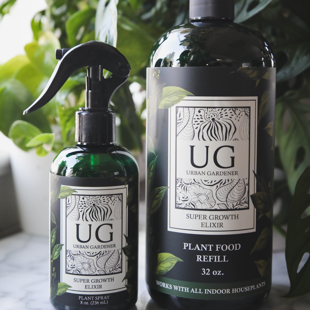 Two bottles of Urban Gardener plant food on a marble surface with plants in the background.