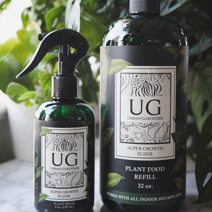 Two bottles of Urban Gardener plant food on a marble surface with plants in the background.